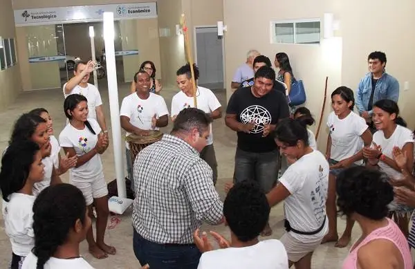 Grupo em roda aplaude uma dinâmica presencial em espaço comunitário.