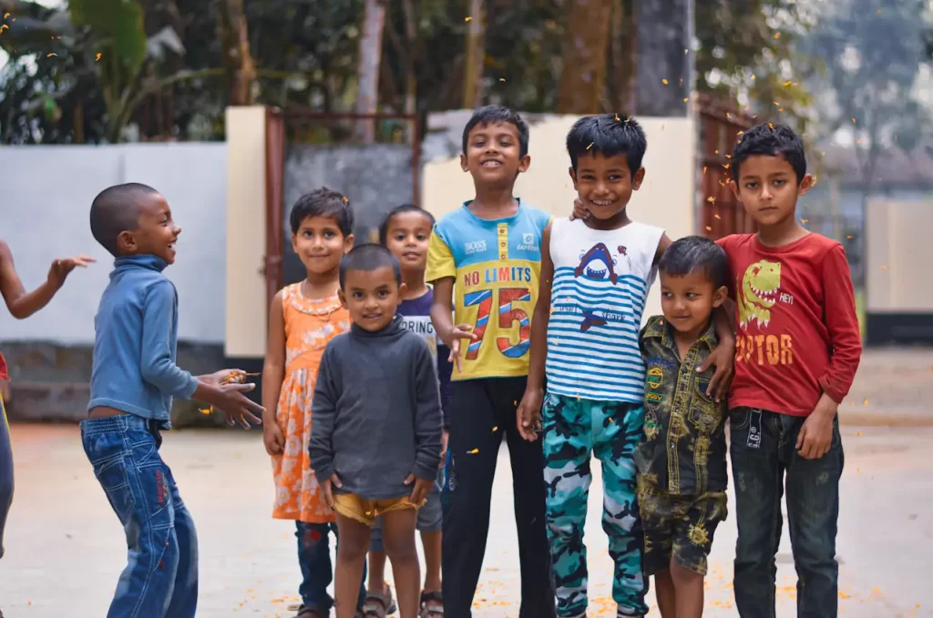 Grupo de crianças posa sorrindo ao ar livre.